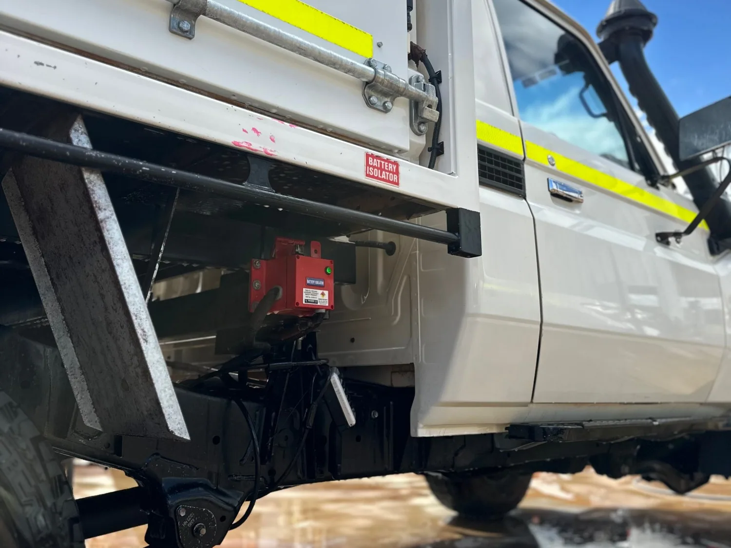 A clean white work ute with a canopy and hi-vis stripes on a wet wash bay