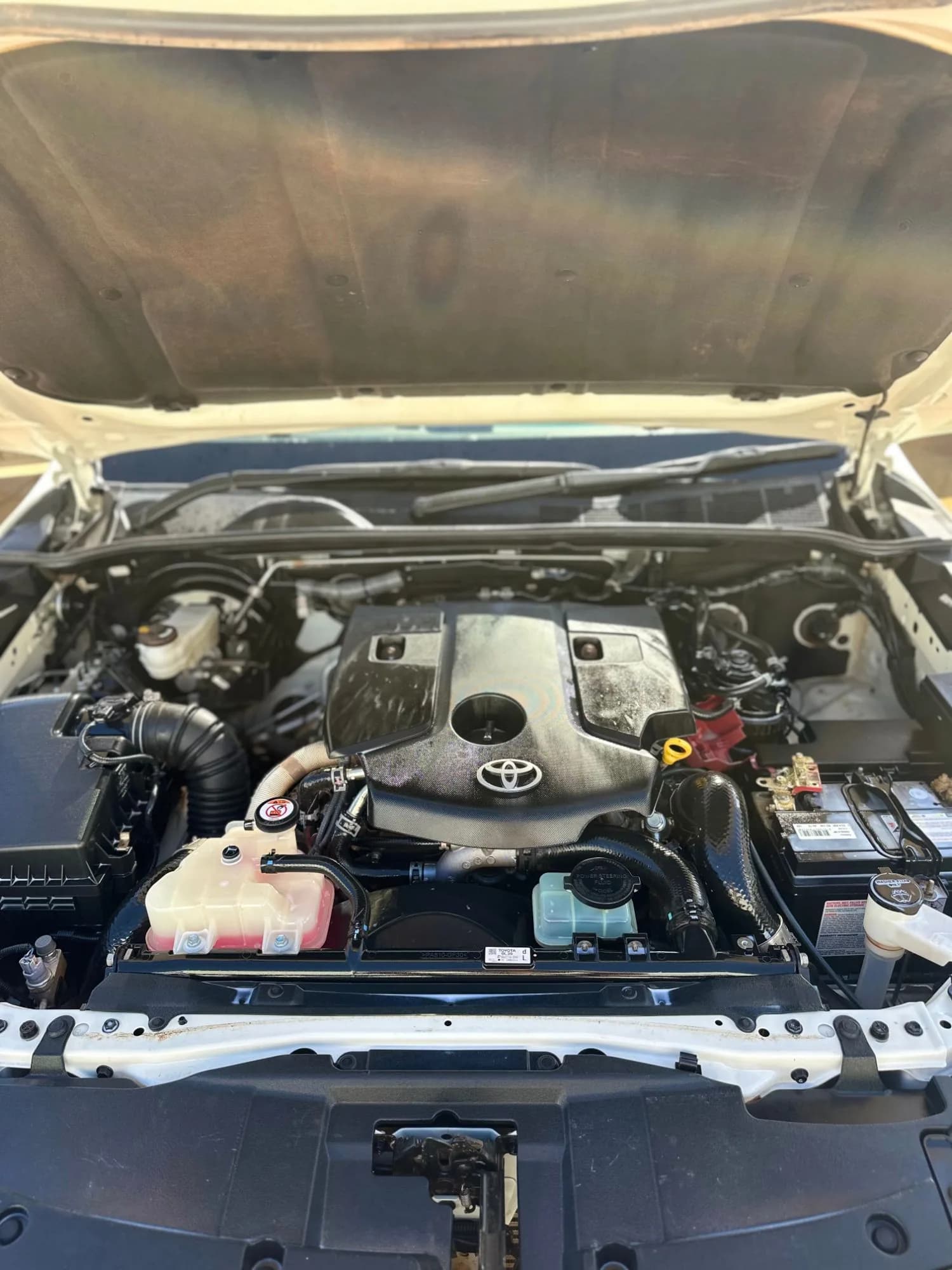 The HiLux engine bay after detailing, with a clean engine cover and battery