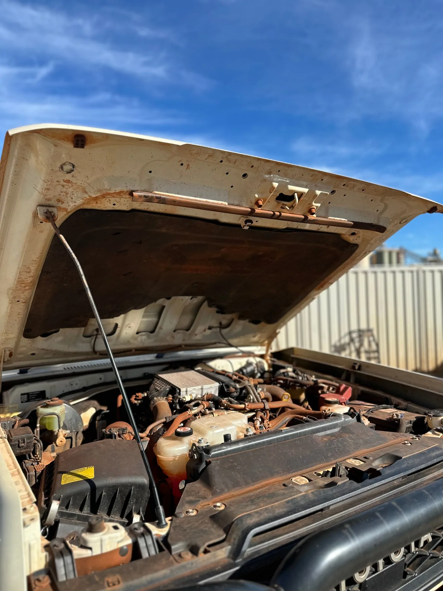 A Toyota LandCruiser engine bay covered in red dust, before detailing